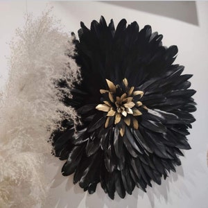 Peut inclure: Une décoration murale en plumes noires avec une fleur dorée au centre. Les plumes sont disposées en cercle, créant un design unique et élégant.