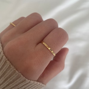 May include: A thin gold band ring with a hammered texture.