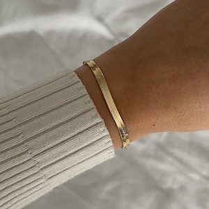 May include: A gold chain bracelet with a snake chain design.