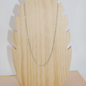 May include: A silver chain necklace displayed on a wooden jewelry stand.