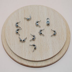 Peut inclure: Caps de perles en métal argenté pour la fabrication de bijoux. Les caps sont ronds et ont un petit trou au centre. Il y a 10 caps au total.