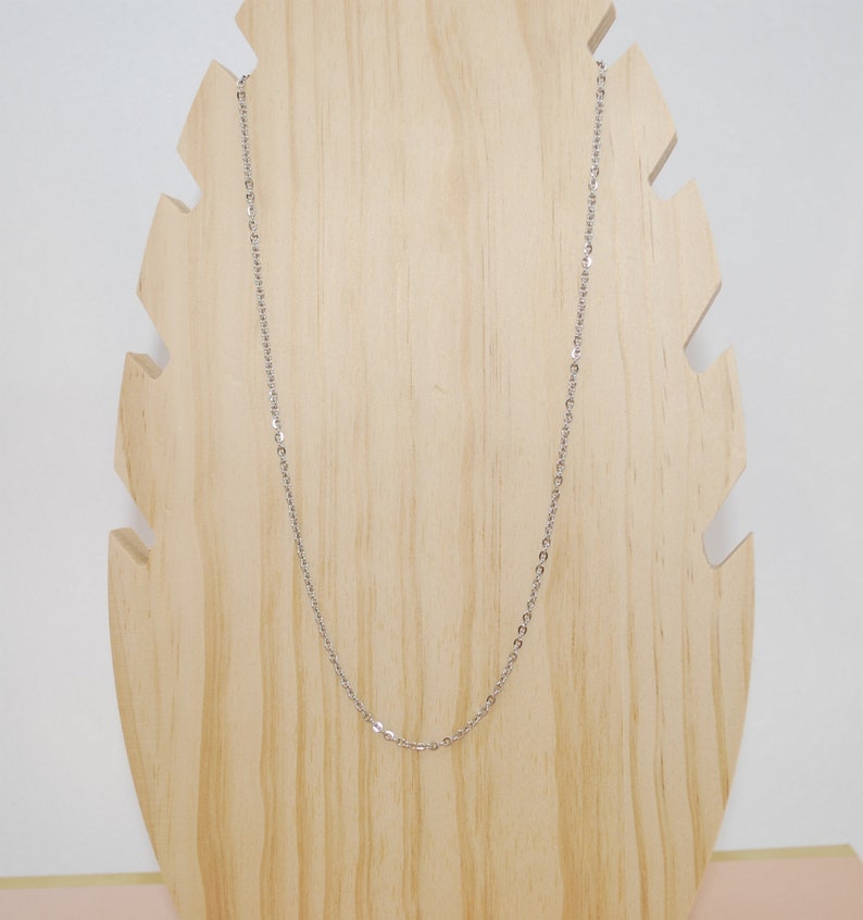 May include: A silver chain necklace on a wooden display stand.