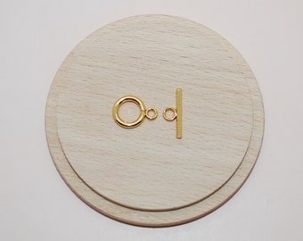 May include: A gold-toned toggle clasp set consisting of a circular ring with an attached small loop and a straight bar with a centered small loop. The components feature a smooth, polished metallic finish and are designed for jewelry assembly.