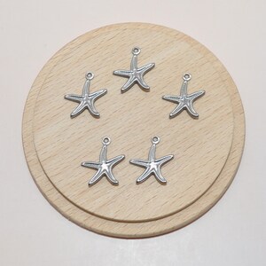 May include: Five silver starfish charms with a loop at the top for attaching to jewelry or other crafts.