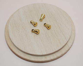 May include: Four gold-colored metal pendant caps with a pointed top and a small hole at the top.