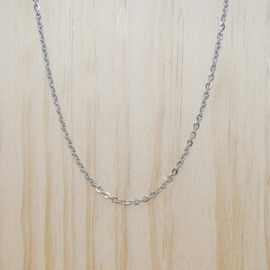 May include: A silver chain necklace on a wooden display stand.