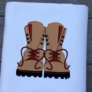 May include: A pair of brown leather hiking boots with red laces. The boots have a black sole and are embroidered on a white fabric.