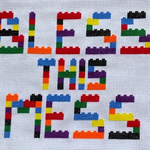 May include: A colorful cross-stitch design with the phrase "Bless this mess" spelled out using colorful Lego-like blocks.