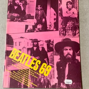 May include: A pink and yellow book cover with the title "Beatles 69" and images of the Beatles band members. The book is part of a series called "The Collected Words and Music".