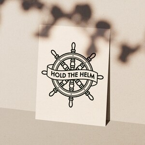 Puede incluir: Ilustración en blanco y negro de línea de arte de un timón de barco con el texto "HOLD THE HELM" en una pancarta.