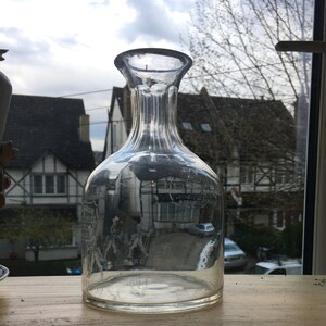 May include: A clear glass decanter with a ribbed neck and etched design. The decanter is empty and appears to be antique.
