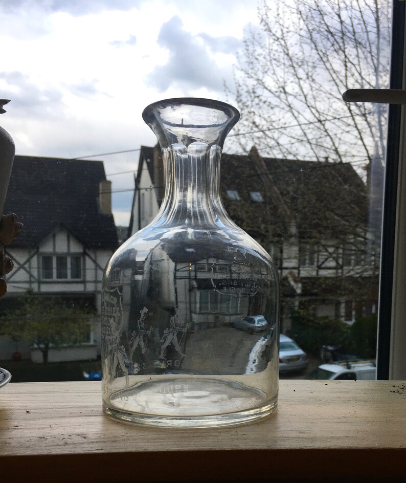 May include: A clear glass decanter with a ribbed neck and etched design. The decanter is empty and appears to be antique.
