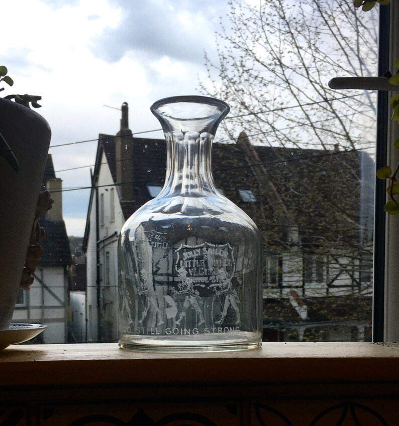 May include: A clear glass decanter with a textured surface and etched text that reads "Jolly Sailors Little Theatre" and "Still Going Strong".