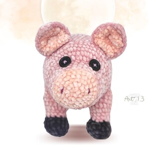 May include: A pink crocheted pig toy with black button eyes. The pig is standing on its four legs and has a textured, fuzzy surface.