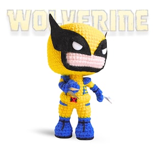 Puede incluir: Un juguete de peluche tejido a crochet de Wolverine de los X-Men. El juguete es amarillo con detalles azules y tiene una máscara negra con ojos blancos.