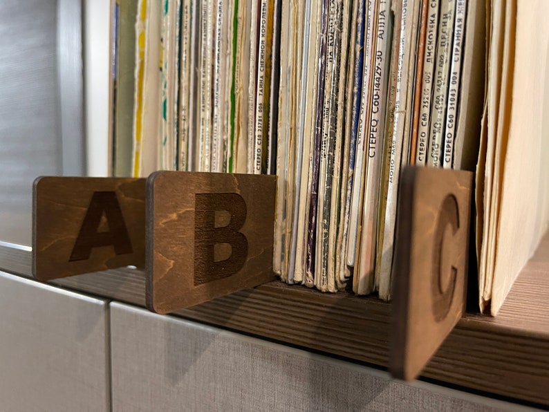 Puede incluir: Tres separadores de madera con las letras A, B y C grabadas en ellos. Los separadores se utilizan para separar los discos de vinilo en un estante.