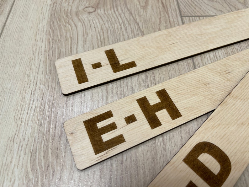 Puede incluir: Tres letreros de madera con letras negras. Los letreros dicen "I-L", "E-H" y "D".