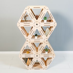May include: A wooden hexagonal shelf unit with six shelves, each shaped like a triangle. The shelves are stacked in a staggered pattern, creating a unique and modern design. The shelves are empty, except for a few small plants and decorative items.