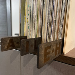 Puede incluir: Tres separadores de madera para una estanter&iacute;a de discos, etiquetados "A-H", "I-L" y "E-H".
