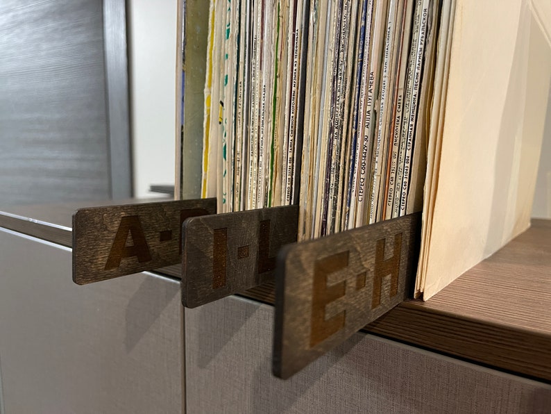 Puede incluir: Tres separadores de madera para una estanter&iacute;a de discos, etiquetados "A-H", "I-L" y "E-H".