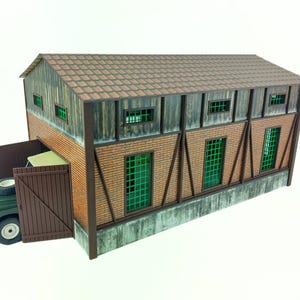 以下が含まれることがあります： 茶色の木の屋根とレンガの壁を持つ建物の詳細なモデル。建物には緑色のフレームの窓と茶色の木のドアがあります。緑色の車両が建物の中に駐車されています。