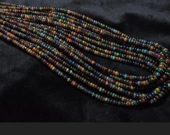 May include: A strand of multi-colored opal beads. The beads are small and round, and they have a variety of colors, including black, green, blue, and red. The beads are strung on a clear thread.