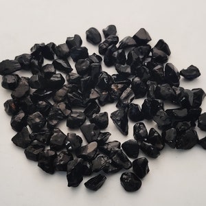May include: A pile of black tumbled stones, likely obsidian or black tourmaline, for use in crafts, jewellery making, or home decor.