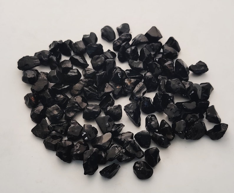 May include: A pile of black tumbled stones, likely obsidian or black tourmaline, for use in crafts, jewellery making, or home decor.