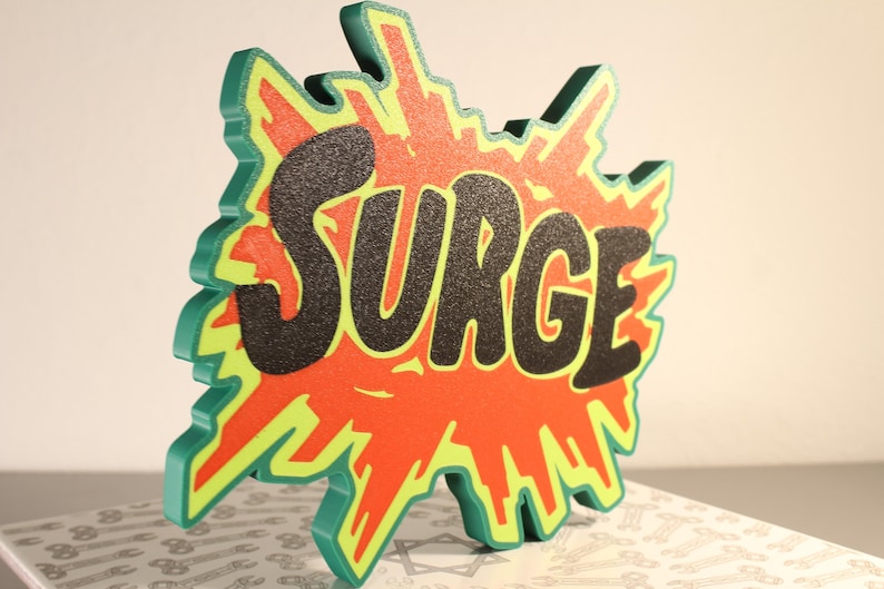 May include: A three-dimensional sign with the word "SURGE" in black, set against a red and yellow burst design. The sign has a green outline and is likely made of wood or a similar material. The sign is displayed on a patterned surface.