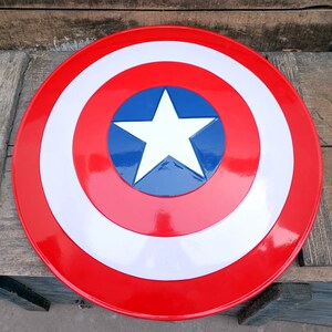 May include: A red, white, and blue Captain America shield with a white star in the center. The shield is made of plastic and is a popular collectible.