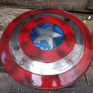 May include: A red, white and blue Captain America shield with a silver star in the centre. The shield has a distressed, weathered look, as if it has been in many battles.