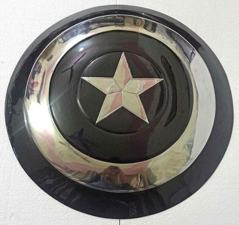 Puede incluir: Una r&eacute;plica de escudo de Capit&aacute;n Am&eacute;rica negro y plateado. El escudo tiene una gran estrella de cinco puntas en el centro.