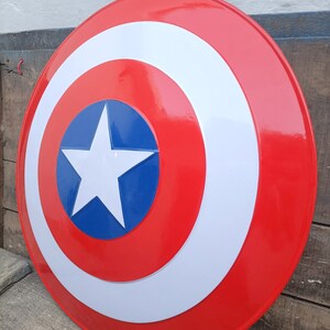 May include: A red, white, and blue Captain America shield with a white star in the center. The shield is made of metal and has a glossy finish.