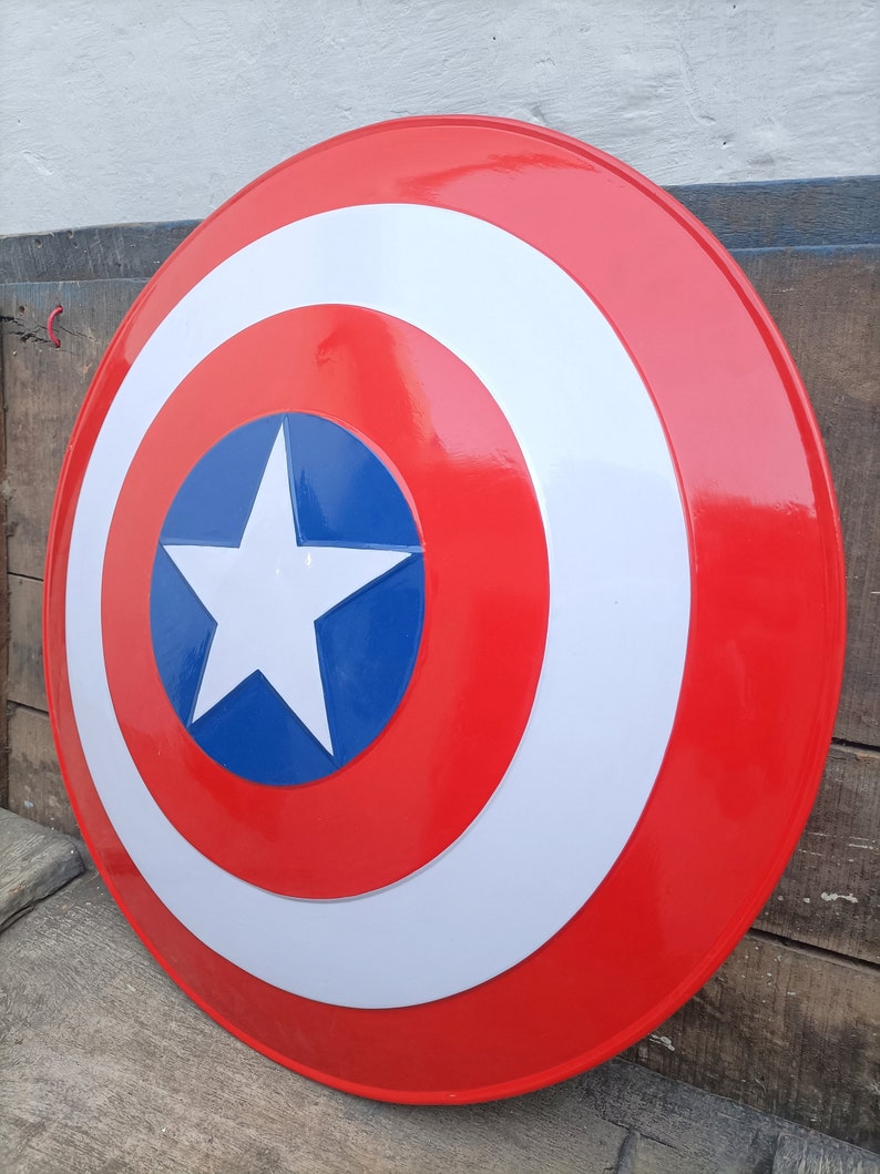 May include: A red, white, and blue Captain America shield with a white star in the center. The shield is made of metal and has a glossy finish.