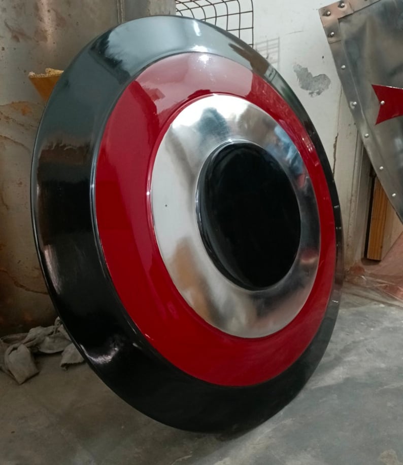 May include: A round shield with a black outer ring, a red middle ring, and a silver inner ring. The center is black. The shield is a prop or decorative item.