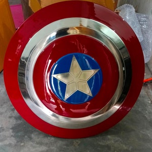 May include: A red, white and blue Captain America shield with a silver metal rim. The shield has a five-pointed star in the centre.
