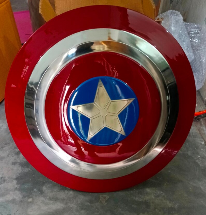 May include: A red, white and blue Captain America shield with a silver metal rim. The shield has a five-pointed star in the centre.