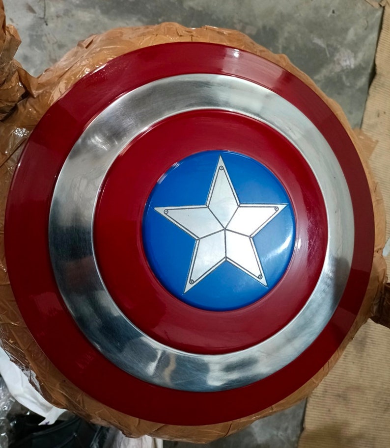 Op de afbeelding: Een rood, wit en blauw Captain America schild met een zilveren ster in het midden. Het schild is gemaakt van metaal en heeft een glanzende afwerking.