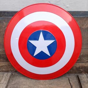 May include: A red, white, and blue Captain America shield with a white star in the center. The shield is round and has a raised rim.