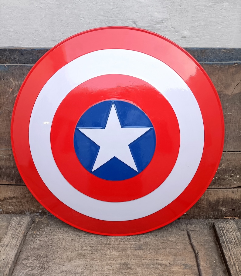 May include: A red, white, and blue Captain America shield with a white star in the center. The shield is round and has a raised rim.