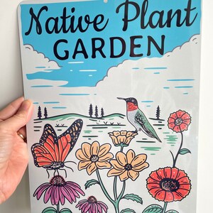Może przedstawiać: Metalowy znak z niebieskim niebem i białymi chmurami w tle. Na znaku widnieje napis "Native Plant Garden" czarnym kolorem. Znak przedstawia r&oacute;wnież kolibra, motyla i kwiaty w r&oacute;żnych kolorach.