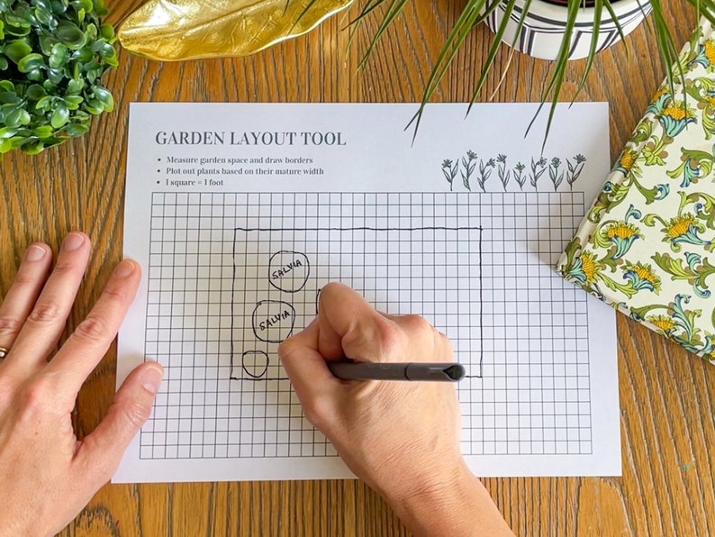 May include: A garden layout tool with a grid pattern and instructions to measure garden space, draw borders, and plot plants based on their mature width. The tool indicates that 1 square equals 1 foot. A hand is drawing circles on the grid and labeling them "SALVIA".