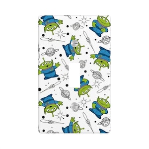 May include: White light switch cover featuring a repeating pattern of green aliens in blue uniforms, planets, stars, and space-themed elements. The switch plate has a single toggle switch opening and two screw holes.