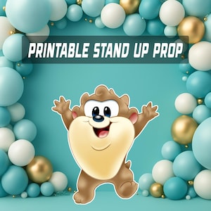 May include: A cartoon character stand-up prop with the text "PRINTABLE STAND UP PROP" against a backdrop of blue, gold, and white balloons. The character is brown and tan with a large smile and outstretched arms, perfect for a party.