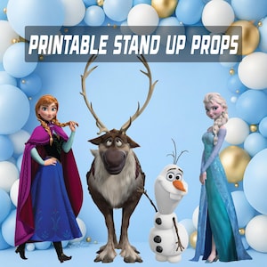 Könnte beinhalten: Ausdruckbare Aufsteller mit Charakteren aus dem Animationsfilm Frozen. Das Bild zeigt Anna in einem blauen Kleid und einem lila Umhang, Elsa in einem blauen Kleid, Olaf den Schneemann und Sven das Rentier, vor einem Hintergrund aus blauen und goldenen Luftballons.