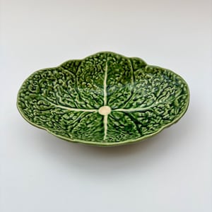 Peut inclure: Un plat de service en céramique vert en forme de feuille de chou. La surface texturée imite les nervures et les plis d'une feuille de chou. Le centre présente un accent de couleur crème.