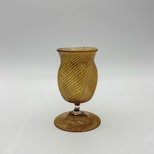 May include: A brown glass goblet with a swirling pattern. The goblet has a wide base and a narrow top.