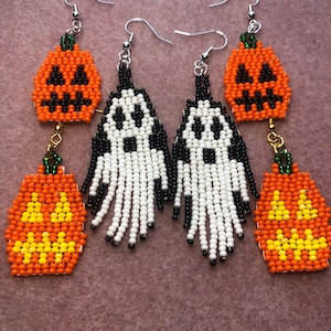 May include: Two pairs of beaded dangle earrings. One pair features orange jack-o'-lanterns with black and yellow details. The other pair features white and black ghosts with fringe-like beaded bottoms. All earrings have silver-toned metal hooks.