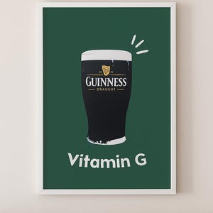 May include: A framed print featuring a pint of Guinness Draught on a dark green background. The Guinness logo is displayed above the pint, with the text "Vitamin G" below. The print is in a white frame.