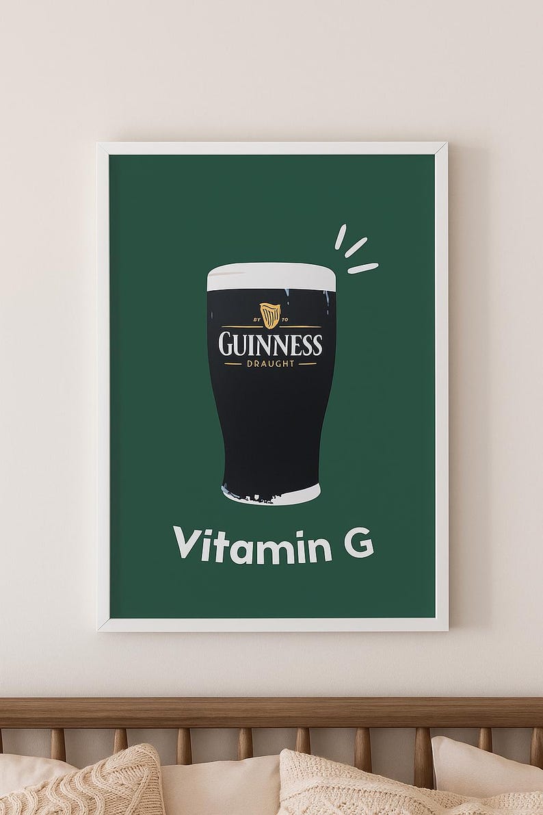 May include: A framed print featuring a pint of Guinness Draught on a dark green background. The Guinness logo is displayed above the pint, with the text "Vitamin G" below. The print is in a white frame.